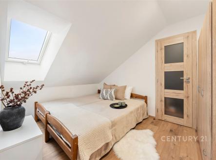 Podkrovní ložnice s parketovou podlahou, světlé dřevo na dveřích a vestavěné skříně, útulný styl s dekorativními prvky. | Prodej bytu, 3+kk, 45 m²