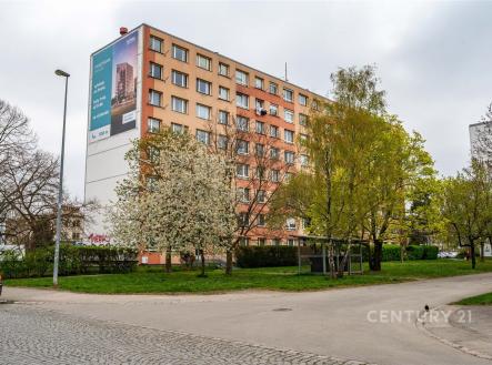 Vícepatrový bytový dům s moderní fasádou, obklopený zelení, stromy a parkovými plochami, vytváří příjemné městské prostředí. | Prodej bytu, 3+kk, 54 m²