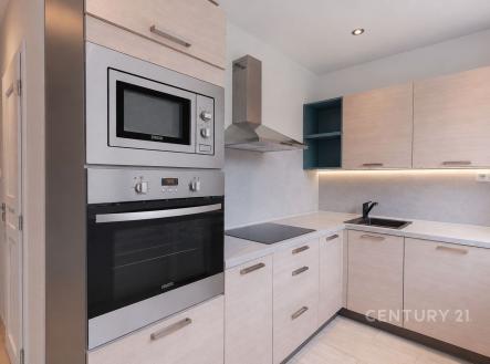 Moderní kuchyň s vestavěnými spotřebiči, světlými skříňkami a dlažbou. Nabízí elegantní úložné prostory a moderní design. | Pronájem bytu, 3+1, 68 m²