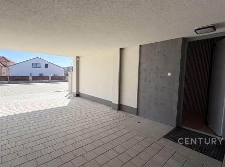 Zastřešené venkovní stání s moderní dlažbou a čistými liniemi nabízí bezpečné parkování a vstup do budovy. | Prodej - dům/vila, 111 m²