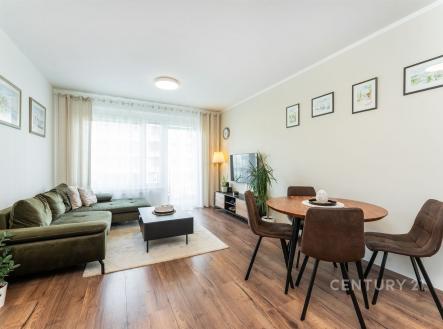 Světlý obývací pokoj s parketovou podlahou a velkými okny, moderní nábytek a jídelní kout vytvářejí útulný prostor | Prodej bytu, 2+kk, 57 m²