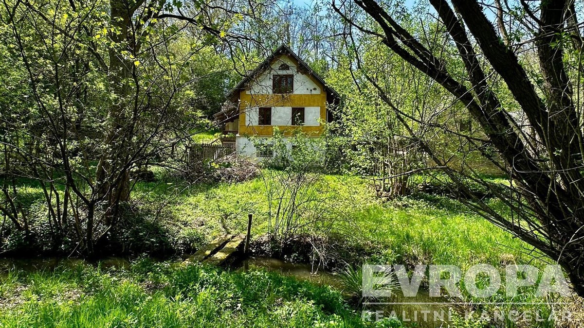 Chata v malebném prostředí s výhledem na les, dřevěné prvky na fasádě, udržovaná zahrada, ideální pro rekreační pobyt.