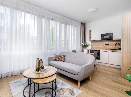Světlý obývací pokoj s moderní kuchyní, parketová podlaha, velká okna s bílými záclonami, elegantní nábytek, světlý a vzdušný interiér. | Pronájem bytu, 1+kk, 35 m²
