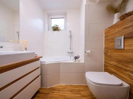 vana s dřevěná podlaha, skříňka pod dřez, přirozené světlo, zrcadlo, a toaleta | Prodej bytu, 3+kk, 60 m²