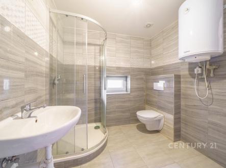 Prostorná koupelna s moderními obklady, sprchovým koutem a závěsnou toaletou, světlá dlažba, bojler na stěně. | Prodej bytu, 2+1, 46 m²