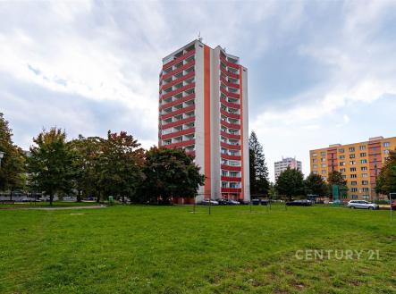 Vysoký bytový dům s balkony, obklopený zeleným parkem a stromy, poblíž parkování. Budova je moderní a nachází se v klidné lokalitě. | Prodej bytu, 3+1, 79 m²
