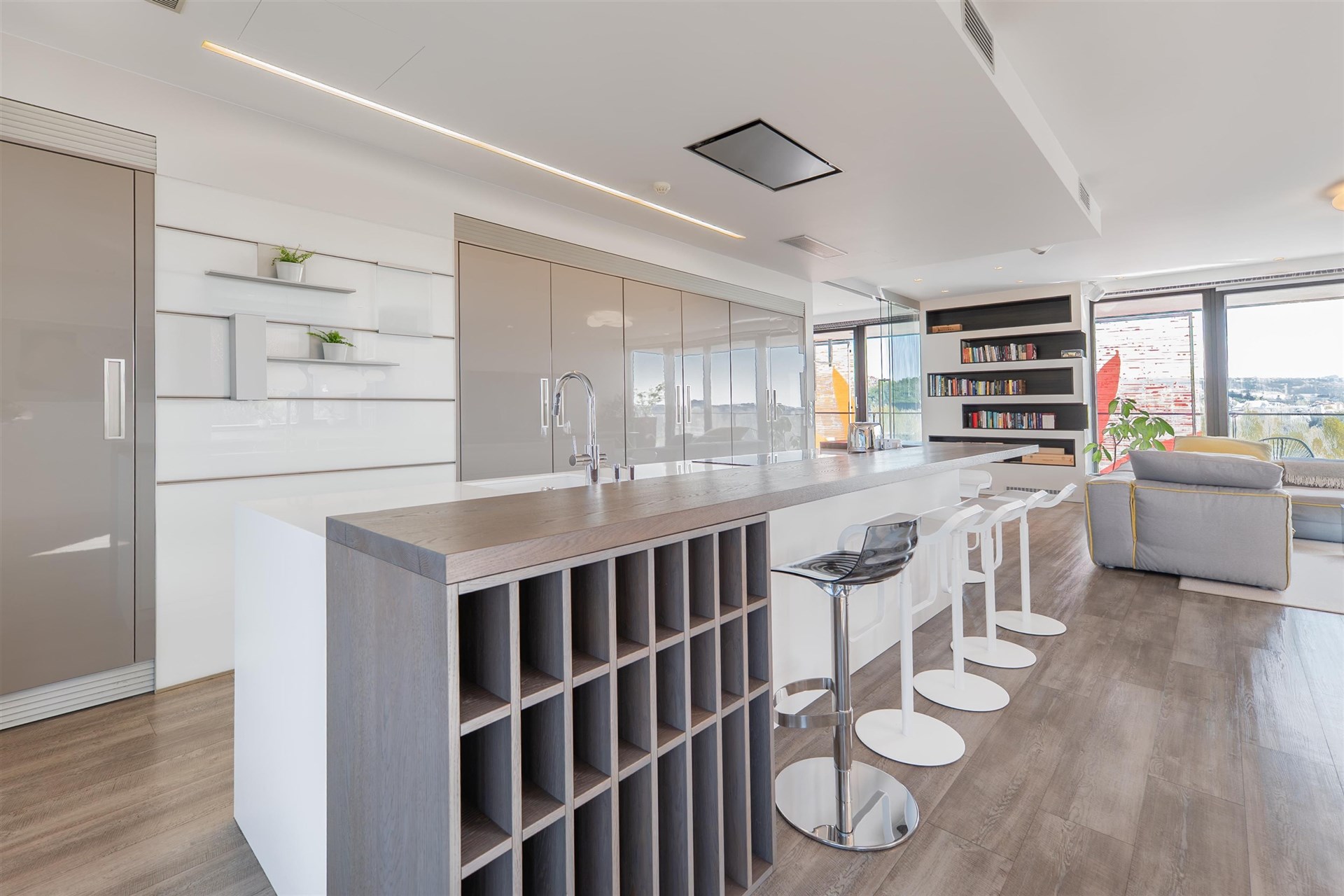 Moderní kuchyň s dřevěnou podlahou, velkým ostrůvkem a elegantními vestavěnými skříněmi, navržena v minimalistickém stylu.