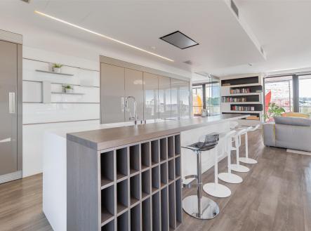 Moderní kuchyň s dřevěnou podlahou, velkým ostrůvkem a elegantními vestavěnými skříněmi, navržena v minimalistickém stylu. | Prodej bytu, 4+kk, 196 m²