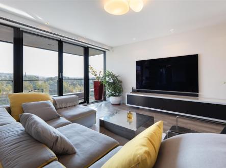 Světlý obývací pokoj s moderním designem, velká okna nabízejí panoramatický výhled, světlá parketová podlaha doplňuje elegantní interiér. | Prodej bytu, 4+kk, 196 m²