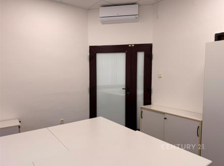 Pracovní kancelář s bílými stěnami, klimatizací a vestavěnou skříní v rohu. | Pronájem - kanceláře, 14 m²