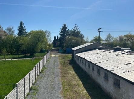 Příjezdová cesta ke starší budově s rekonstrukčním potenciálem, obklopená zelení a venkovským prostředím, ideální pro investici. | Prodej - skladovací prostor, 726 m²
