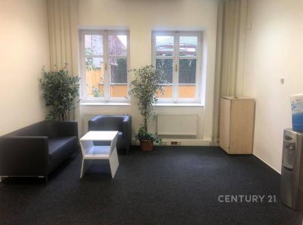 Světlý obývací pokoj s tmavou kobercovou podlahou, velkými okny a moderním nábytkem, ideální pro příjemné posezení. | Pronájem - kanceláře, 52 m²