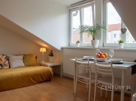Podkrovní obývací pokoj s parketovou podlahou, velká okna propouštějící světlo, moderní nábytek a útulná atmosféra | Prodej bytu, 2+kk, 36 m²