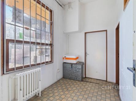 Vstupní hala s dlažbou, velkým oknem a bílými stěnami, nabízí prostor pro úložné řešení, vhodná pro renovaci. | Pronájem - obchodní prostor, 64 m²