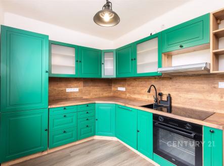 Moderní kuchyň s dřevěnou pracovní deskou, zelenými skříňkami a vestavěnou troubou. Stylový design doplňuje světlá parketová podlaha. | Prodej bytu, 3+1, 67 m²