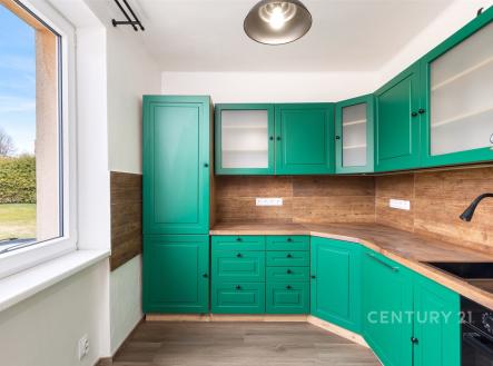 Kuchyň s dřevěnými prvky, moderními zelenými skříněmi a velkým oknem, dřevěný vzhled pracovní desky, světlý prostor. | Prodej bytu, 3+1, 67 m²