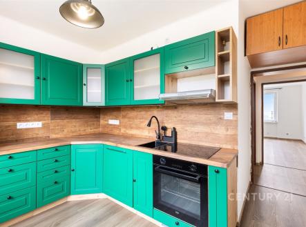 Moderní kuchyň s dřevěnými povrchy a zelenými skříňkami, vestavěná trouba, laminátová podlaha, světlá a otevřená dispozice. | Prodej bytu, 3+1, 67 m²