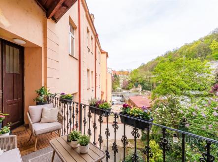 Balkon s dřevěnou dlažbou, výhledem na zelené prostředí a ozdobným kovovým zábradlím, vhodný pro relaxaci v klidné části města | Prodej bytu, 3+1, 99 m²