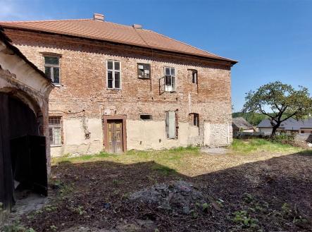 Velký venkovský dům s cihlovou fasádou a šikmou střechou, vyžadující rekonstrukci, obklopený rozlehlým pozemkem. | Prodej - dům/vila, 264 m²