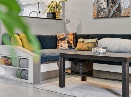 Moderní obývací pokoj s dlažbou, moderní sedačkou a dekorativními polštáři, doplněný elegantním konferenčním stolkem a uměleckým obrazem na stěně. | Prodej - dům/vila, 100 m²