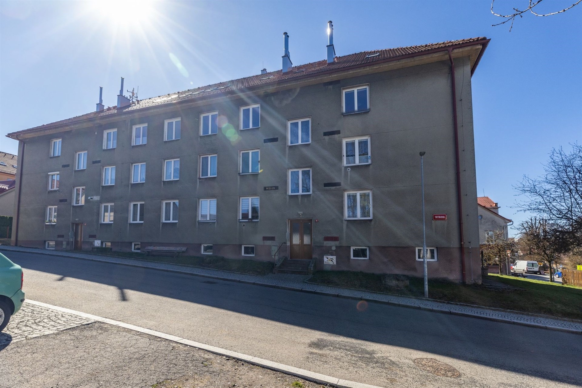 Bytový dům s moderní fasádou, plastovými okny a šikmou střechou, umístěný v klidné rezidenční čtvrti s dobrou dostupností služeb.