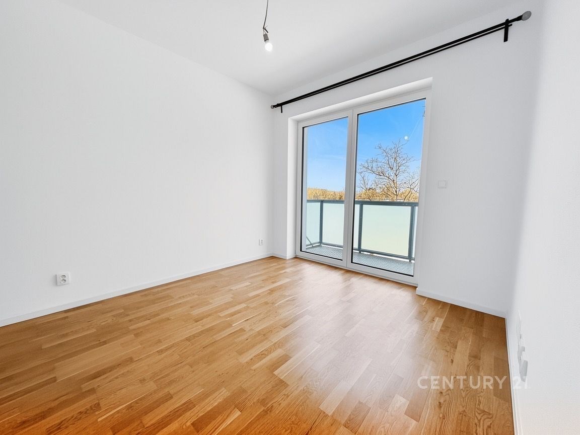 Prostorná ložnice s parketovou podlahou a velkými okny, moderní design, vhodná pro relaxaci, skvělá světlost díky velkým francouzským dveřím.