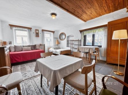 Světlý obývací pokoj s kamennou dlažbou, dřevěným stropem a velkými okny, obsahuje dřevěný nábytek a jídelní kout, působí útulně. | Prodej - chata/rekreační objekt, 156 m²