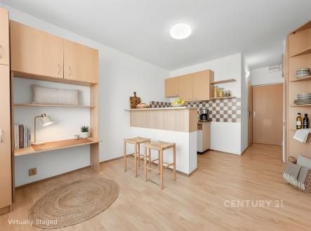 Kompaktní kuchyň s parketovou podlahou, dřevěnými skříňkami a moderními světly, vedle vestavěného pracovního prostoru s policemi. | Prodej bytu, 1+kk, 20 m²