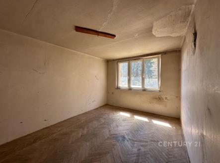 Prázdná místnost s parketovou podlahou a velkými okny, vyžadující rekonstrukci, s popraskanou stěnou a stropem. | Prodej bytu, 1+1, 41 m²