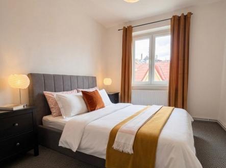 Prostorná ložnice s moderním stylem, kobercová podlaha, velká okna zajišťující světlý interiér, elegantní osvětlení, útulná atmosféra. | Pronájem bytu, 3+kk, 70 m²