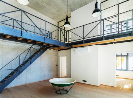 Industriální obývací pokoj s parketovou podlahou, kovovým schodištěm a vysokými stropy, moderní design a velká okna přináší světlost. | Prodej bytu, atypický, 181 m²