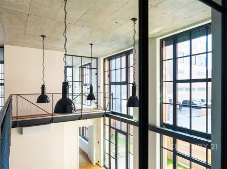 Moderní interiér s vysokým stropem, velká okna a parketová podlaha, industriální styl s kovovými prvky, ideální pro loftové bydlení. | Prodej bytu, atypický, 181 m²