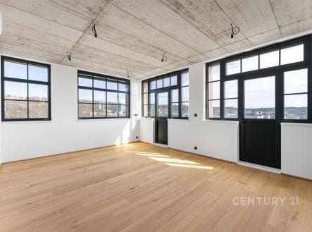 Světlý obývací pokoj s parketovou podlahou, velkými okny a moderním industriálním stylem, ideální pro široké využití. | Prodej bytu, 2+kk, 48 m²