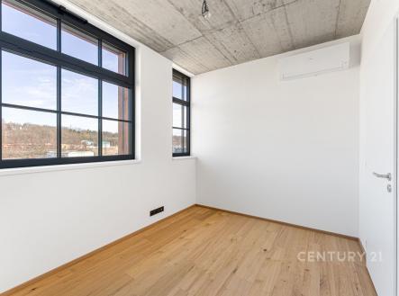 Útulná místnost s parketovou podlahou, velkými okny a moderními prvky, jako je betonový strop a bílé stěny, nabízí světlý prostor. | Prodej bytu, 2+kk, 48 m²