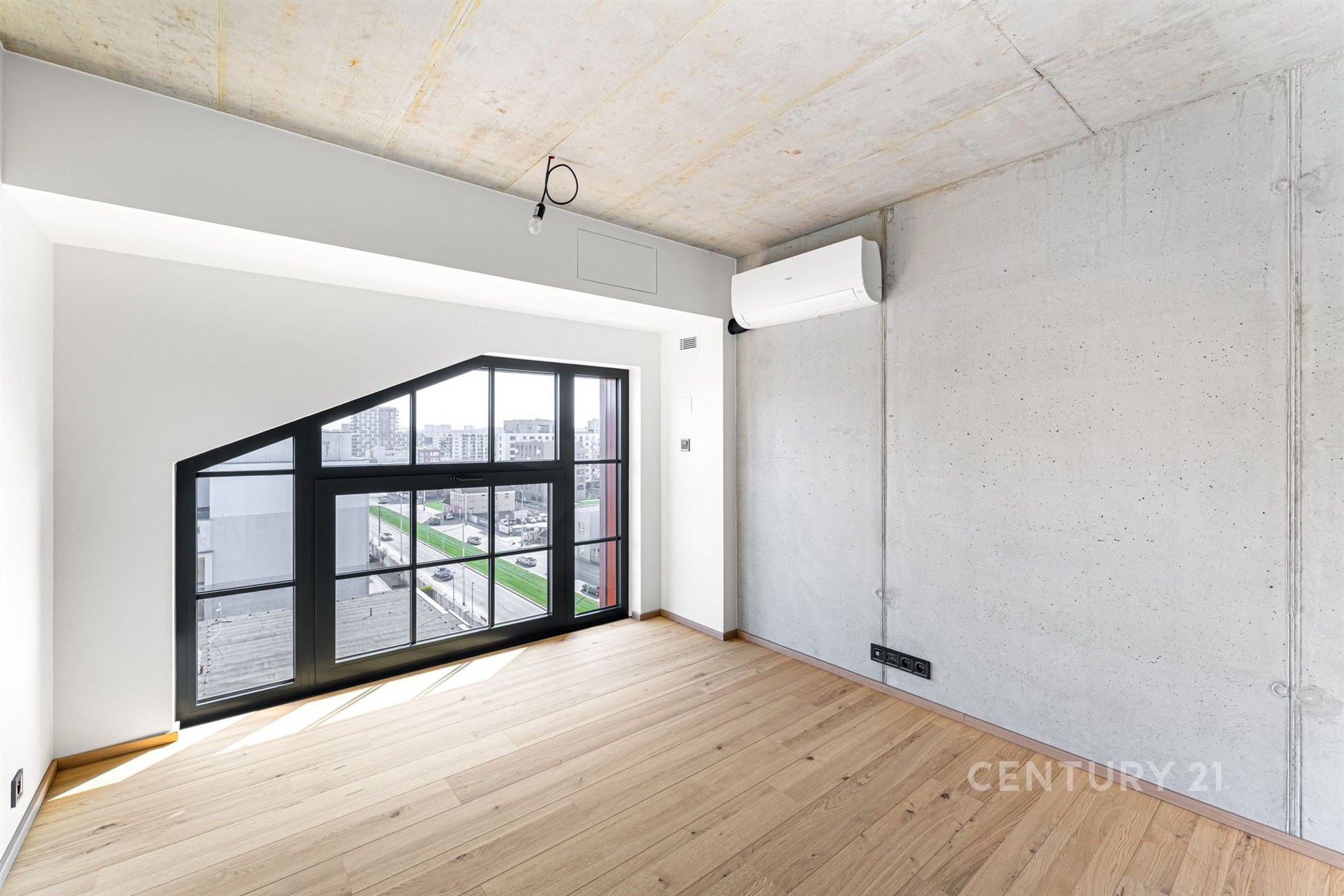 Světlý obývací pokoj s velkými okny, parketovou podlahou a moderním industriálním stylem.