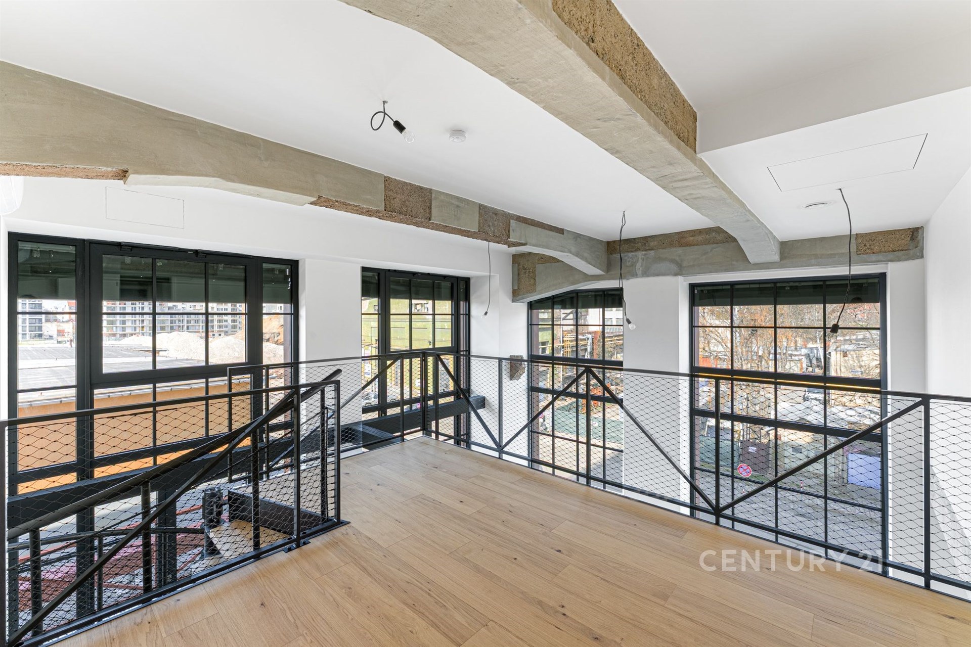 Světlá chodba s parketovou podlahou a velkými okny, moderní styl s kovovým zábradlím, ideální pro loftový byt.