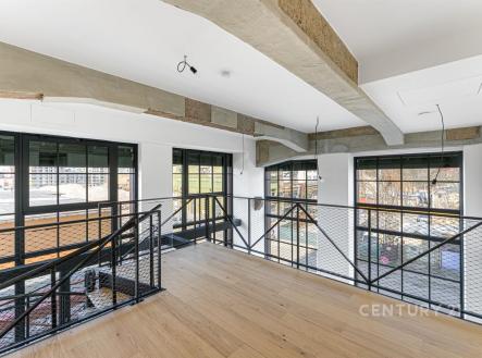 Světlá chodba s parketovou podlahou a velkými okny, moderní styl s kovovým zábradlím, ideální pro loftový byt. | Prodej bytu, 4+kk, 110 m²