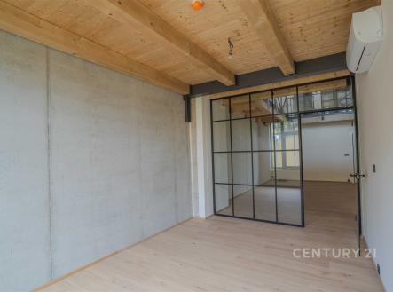 Průmyslový interiér s dřevěnými stropy, betonovými stěnami a skleněnými integrovanými dveřmi. Moderní design s kvalitními materiály. | Prodej bytu, 4+kk, 176 m²