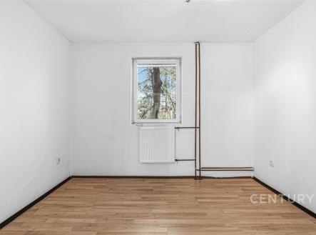 Prázdný pokoj s parketovou podlahou, bílými stěnami a oknem s výhledem na přírodu, vhodný pro rekonstrukci a vlastní designové úpravy. | Prodej - dům/vila, 144 m²