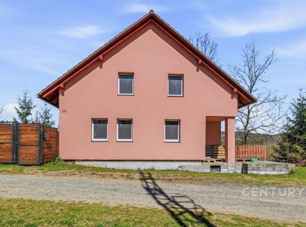 Čelní pohled na moderní rodinný dům s růžovou fasádou, červenou střechou a plastovými okny, obklopený přírodou a oplocením. | Prodej - dům/vila, 144 m²