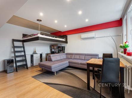 Světlý obývací pokoj s parketovou podlahou, velká okna, moderní klimatizace a podkrovní lůžko vytvářejí útulný a funkční prostor. | Prodej bytu, 2+1, 56 m²