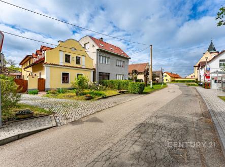 Ulice s rodinnými domy, dlážděný chodník a udržovaná zeleň. Klidná rezidenční čtvrť s tradiční architekturou. | Prodej - dům/vila, 245 m²