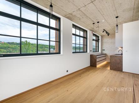 Světlý obývací pokoj s parketovou podlahou a velkými okny, moderní betonový strop, minimalistický design, přírodní výhled | Pronájem bytu, 3+kk, 74 m²