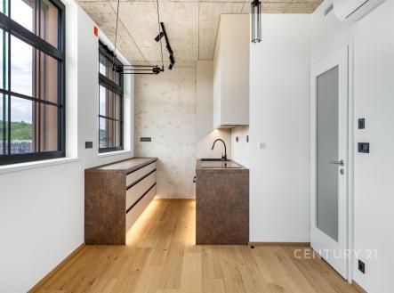 Moderní kuchyň s parketovou podlahou, velká okna a elegantní vestavěné skříně, strop z betonu dodává industriální vzhled. | Pronájem bytu, 3+kk, 74 m²
