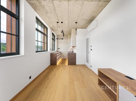 Moderní kuchyň s dřevěnou podlahou a velkými okny, betonový strop, otevřený prostor s vestavěnými spotřebiči. | Pronájem bytu, 3+kk, 74 m²
