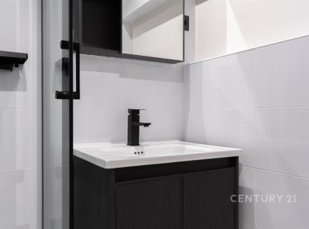 Moderní koupelna s černými doplňky, elegantní dlažbou a kvalitním sprchovým koutem vytváří funkční a stylový prostor. | Prodej bytu, 2+1, 58 m²