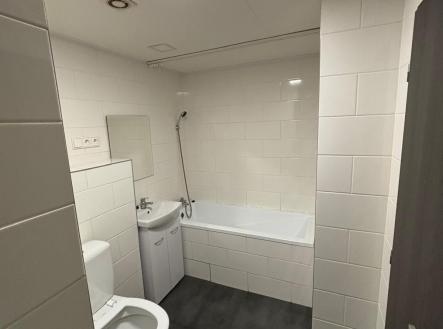 Koupelna s dlažbou, bílými obklady a vanou, vybavená moderním sanitárním zařízením, ideální pro rekonstruovaný byt. | Pronájem bytu, 3+1, 69 m²