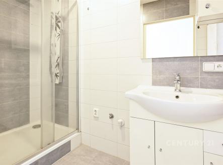 Moderní koupelna s betonovou dlažbou, sprchovým koutem a bílým umyvadlem. Kombinace šedých a bílých obkladů vytváří čistý vzhled. | Pronájem bytu, 2+1, 53 m²