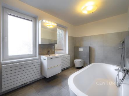 Prostorná koupelna s moderní dlažbou, velkými okny a novým osvětlením nabízí elegantní a světlý prostor k relaxaci. | Prodej - dům/vila, 217 m²