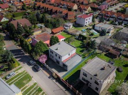 Letecký pohled na klidnou rezidenční čtvrť s moderními rodinnými domy, zahradami a dlážděnými příjezdovými cestami. | Prodej - dům/vila, 217 m²